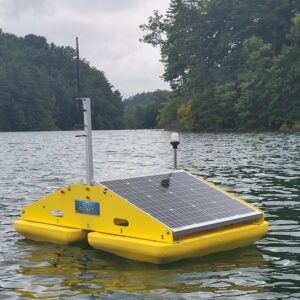 A floating yellow ultrasonic algae control raft with attached solar panels to power the ultrasonic transducer unit that is suspended into the water below the raft